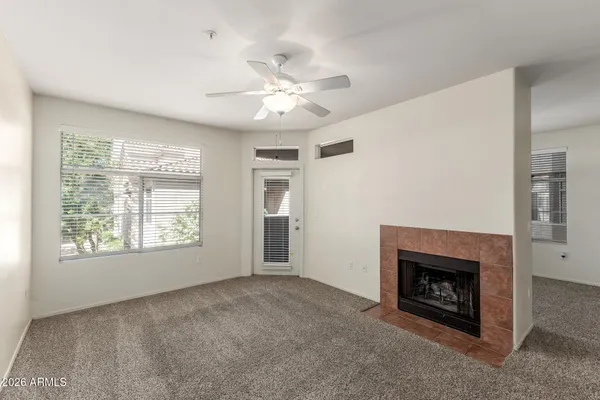 a view of an empty room with chandelier fan and fire place