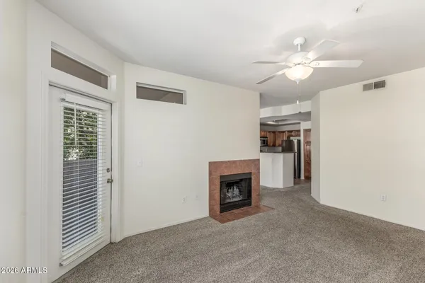 an empty room with windows fireplace and fan