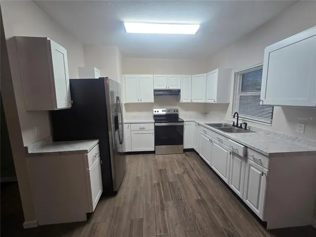 a kitchen with stainless steel appliances a refrigerator a sink a stove a microwave a counter space and cabinets