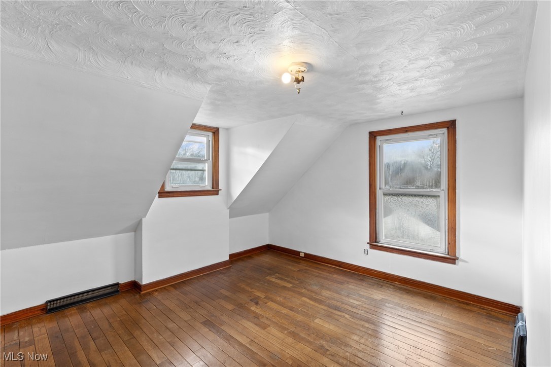 102 Potrock Road Wellsburg, WV 26070 - Photo 20 of 42 Additional living space featuring wood-type flooring, vaulted ceiling, a textured ceiling, and a baseboard radiator