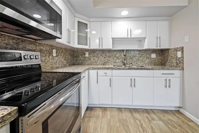 a kitchen with granite countertop a stove and white cabinets