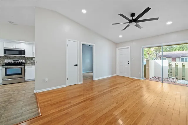 a view of empty room with wooden floor and fan