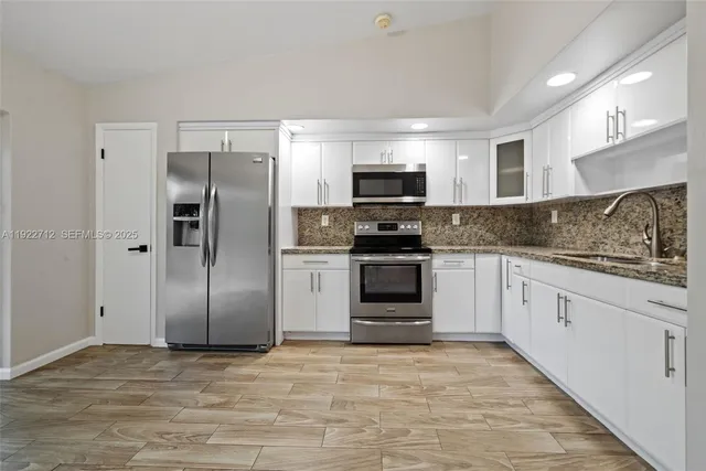 a kitchen with stainless steel appliances granite countertop a refrigerator sink and stove