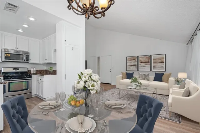 a kitchen with stainless steel appliances kitchen island granite countertop a dining table chairs and a microwave