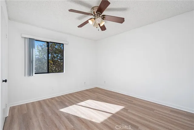 an empty room with a ceiling fan and wooden floor