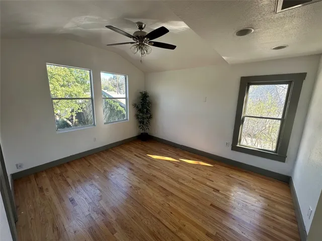 a view of empty room with wooden floor and fan