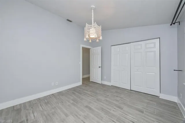 a view of an empty room with wooden floor and chandelier