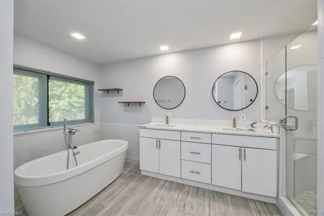 a bathroom with a double vanity sink a toilet a mirror and bathtub