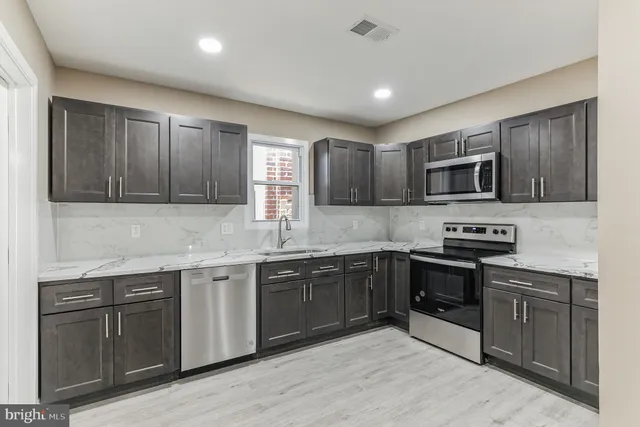 a kitchen with stainless steel appliances granite countertop wooden cabinets a stove top oven a sink and dishwasher
