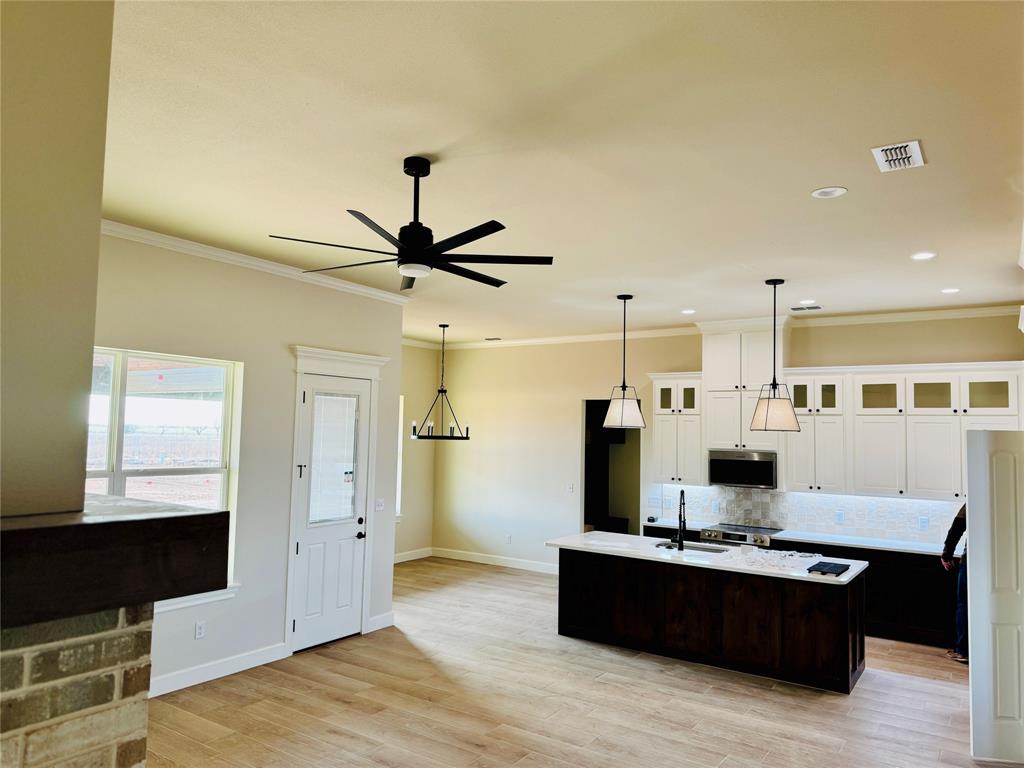 245 Indian Ridge Road Tuscola, TX 79562 - Photo 10 of 21 Kitchen featuring white cabinetry, ornamental molding, an island with sink, glass insert cabinets, and appliances with stainless steel finishes