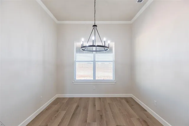 an empty room with wooden floor exposed radiator and a window