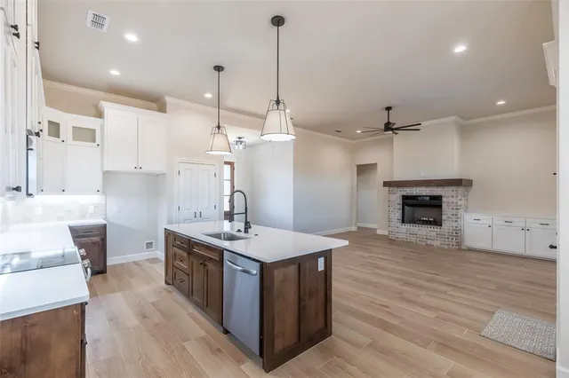 a large kitchen with stainless steel appliances a stove a sink dishwasher and a wooden floor