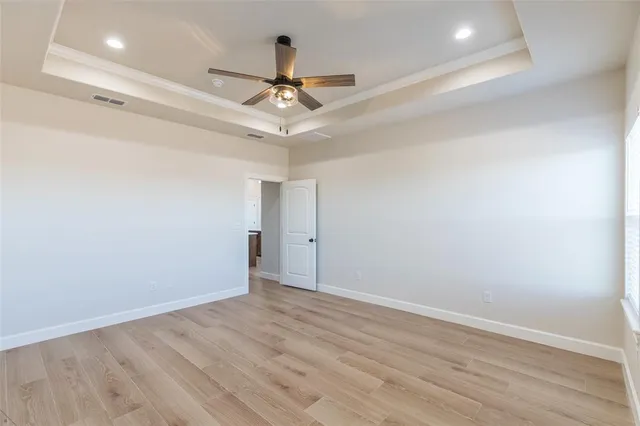 a view of an empty room with wooden floor and a ceiling fan