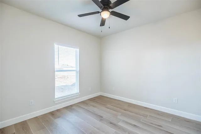 an empty room with a window and a fan
