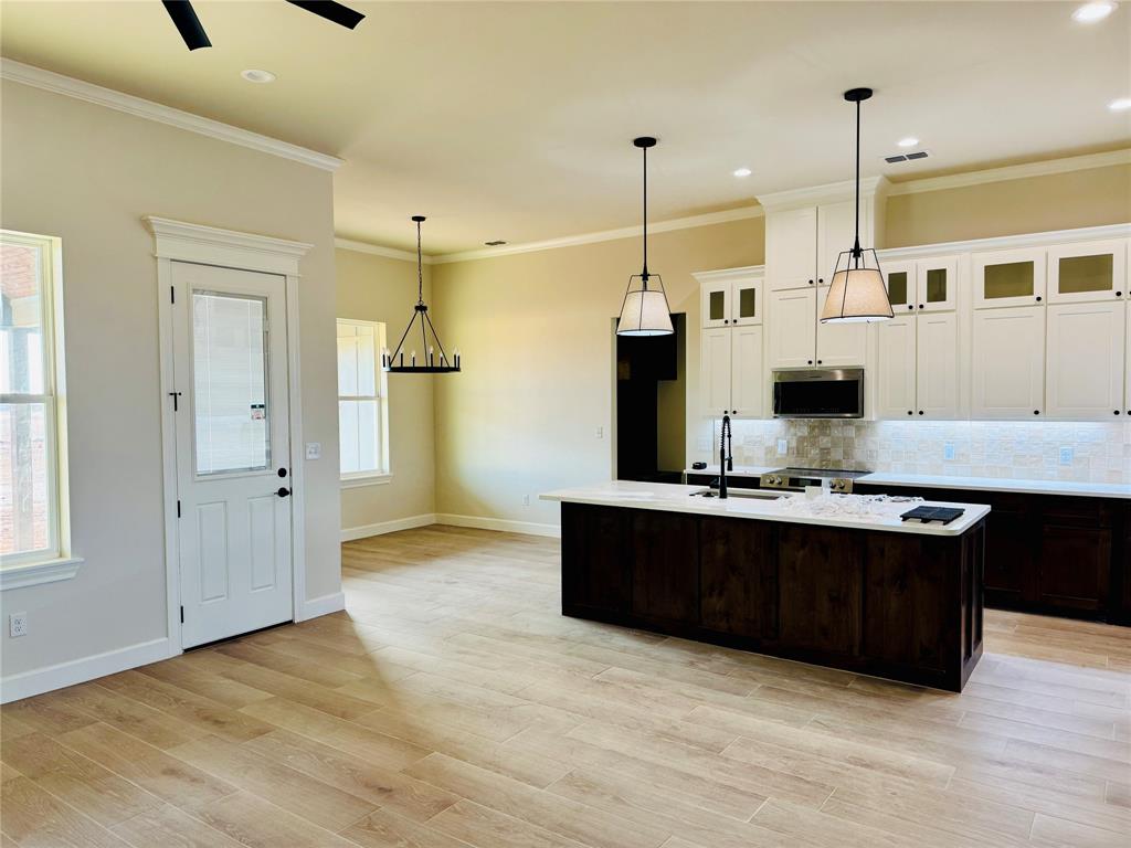 245 Indian Ridge Road Tuscola, TX 79562 - Photo 5 of 21 Kitchen with white cabinets, a kitchen island with sink, dark brown cabinetry, glass insert cabinets, and crown molding