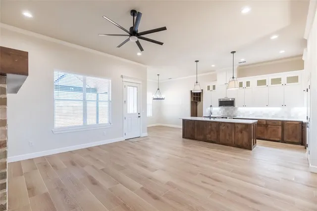 a large white kitchen with kitchen island a large counter top space a sink stainless steel appliances and windows
