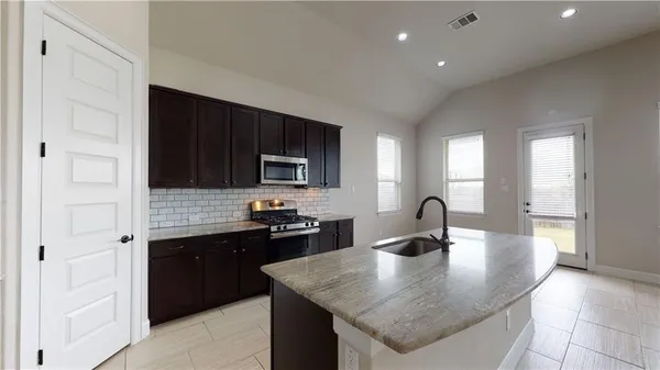 a kitchen with granite countertop a stove a sink and a microwave