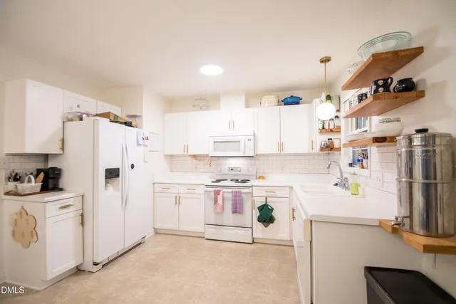 a kitchen with white cabinets and refrigerator