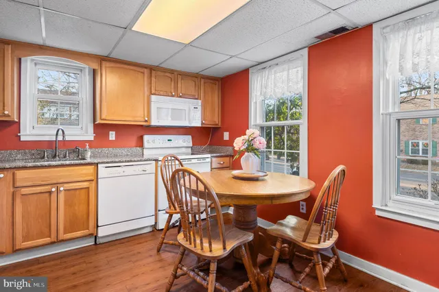 a kitchen with stainless steel appliances granite countertop a stove a sink dishwasher a dining table and chair with wooden floor