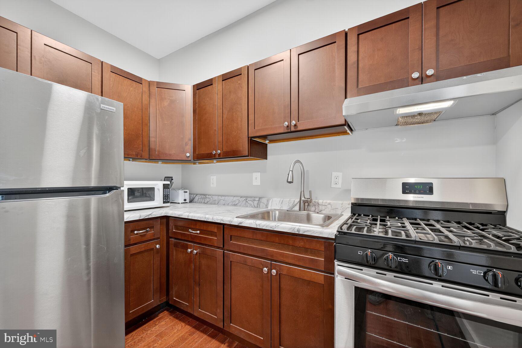 1440 W Street Northwest, Unit 106 Washington, DC 20009 - Photo 8 of 25 a kitchen with stainless steel appliances granite countertop a stove a refrigerator and a sink