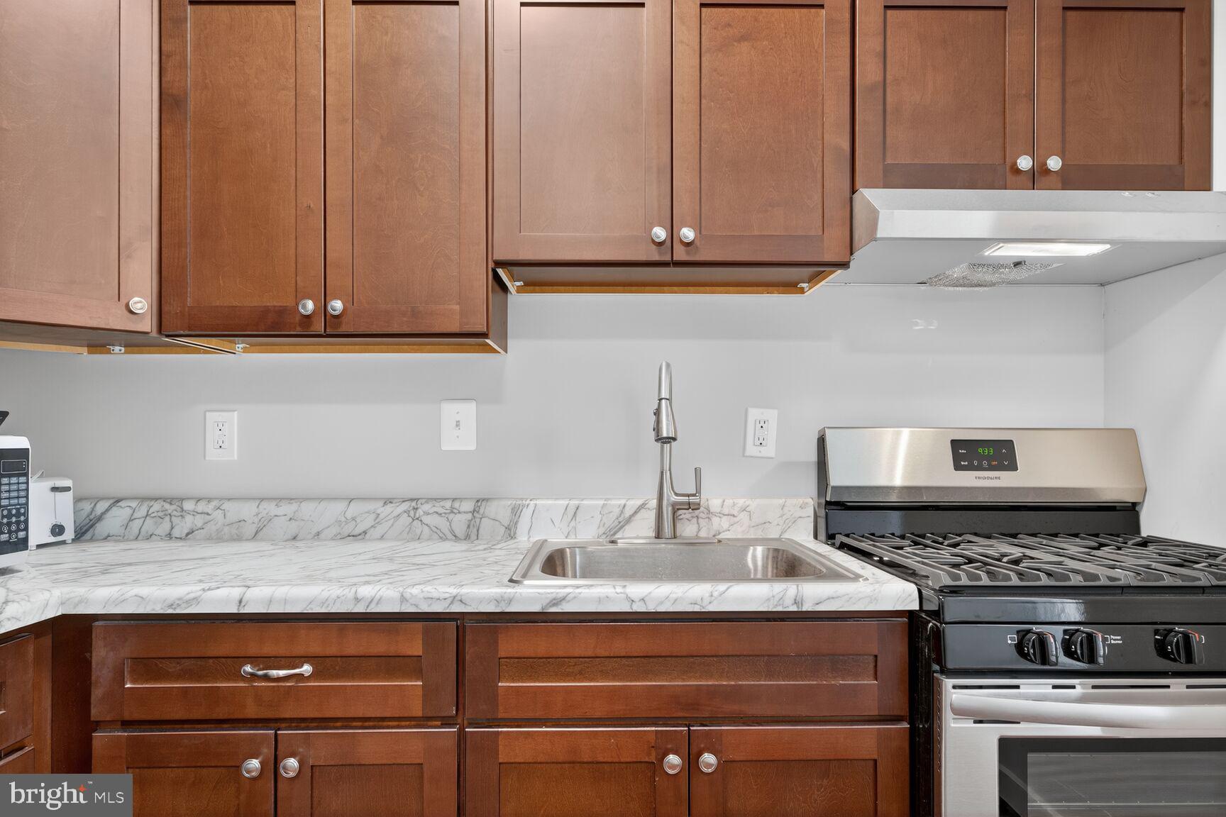 1440 W Street Northwest, Unit 106 Washington, DC 20009 - Photo 10 of 25 a kitchen with granite countertop a stove a sink and dishwasher