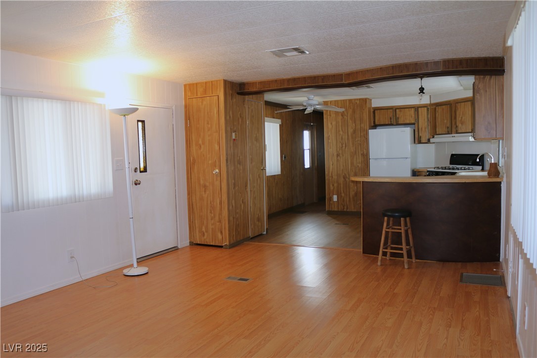 4633 Royal Ridge Boulevard Las Vegas, NV 89103 - Photo 4 of 13 Kitchen with freestanding refrigerator, brown cabinetry, gas stove, visible vents, and light wood-style floors