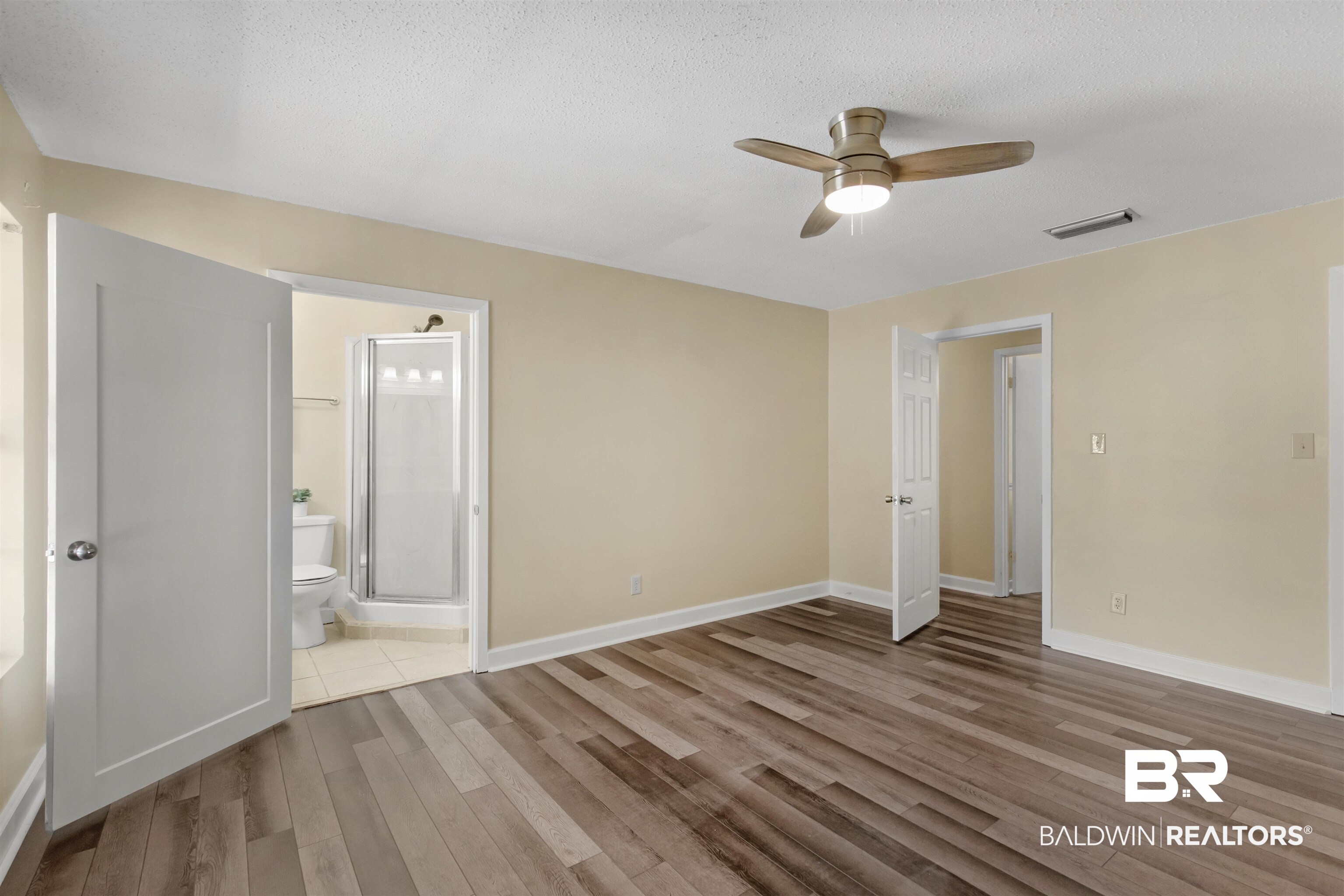 5665 Ulysses Road Eight Mile, AL 36613 - Photo 10 of 23 Unfurnished bedroom with ensuite bathroom, wood finished floors, a textured ceiling, baseboards, and visible vents