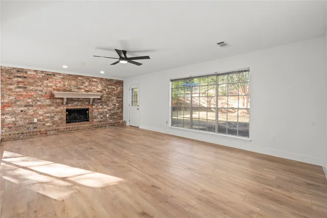 an empty room with chandelier fan and windows
