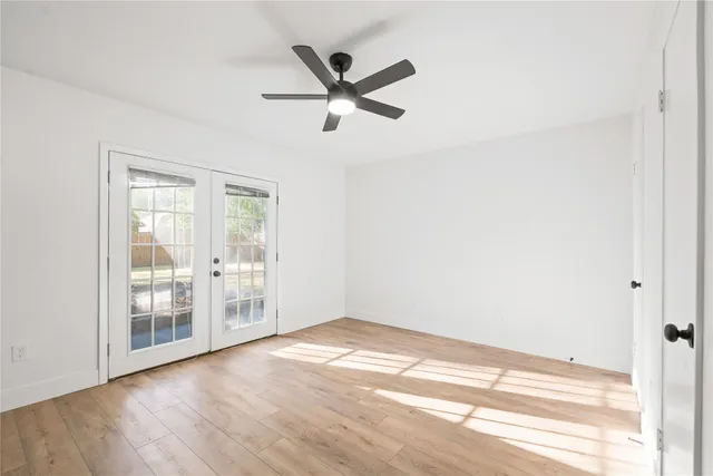 a view of empty room with wooden floor and fan