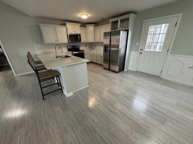 a room with stainless steel appliances wooden floors and view living room