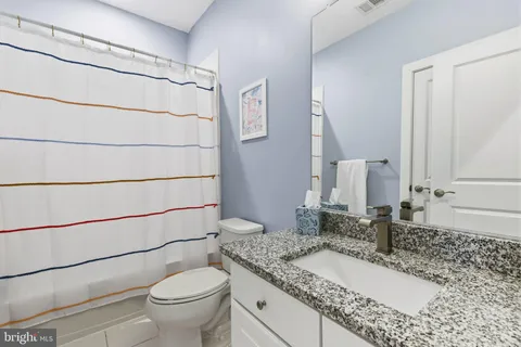 a bathroom with a granite countertop sink toilet and shower