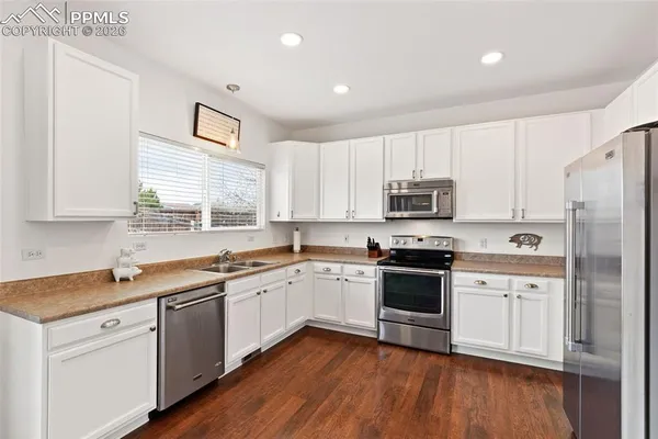 a kitchen with a sink white cabinets and white appliances
