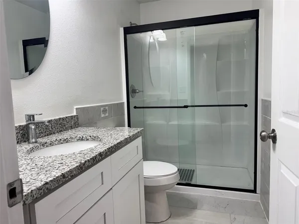 a bathroom with a granite countertop sink a toilet and a shower