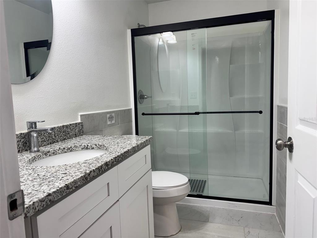 38706 River Road Dade City, FL 33525 - Photo 14 of 30 a bathroom with a granite countertop sink a toilet and a shower