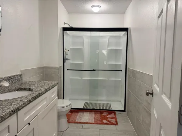 a bathroom with a granite countertop shower sink and mirror