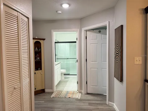 a view of a hallway with wooden floor and a bathroom