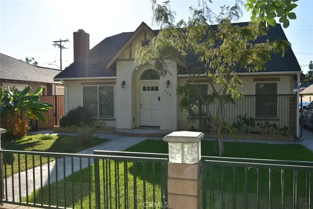 a view of a house with a small yard plants and large tree