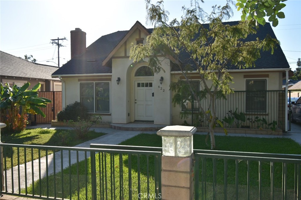 a view of a house with a small yard plants and large tree