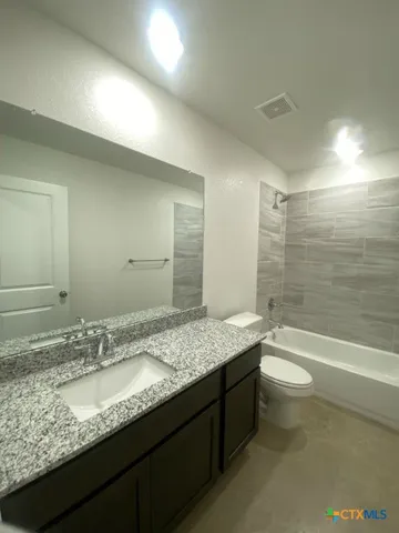 a bathroom with a granite countertop sink a toilet and bathtub