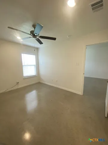 an empty room with windows and fan
