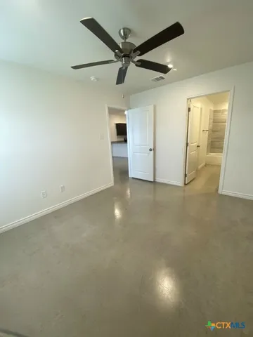 an empty room with ceiling fan and windows