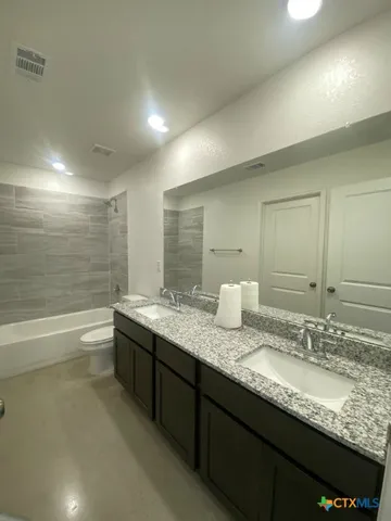a bathroom with a granite countertop bathtub sink double and mirror