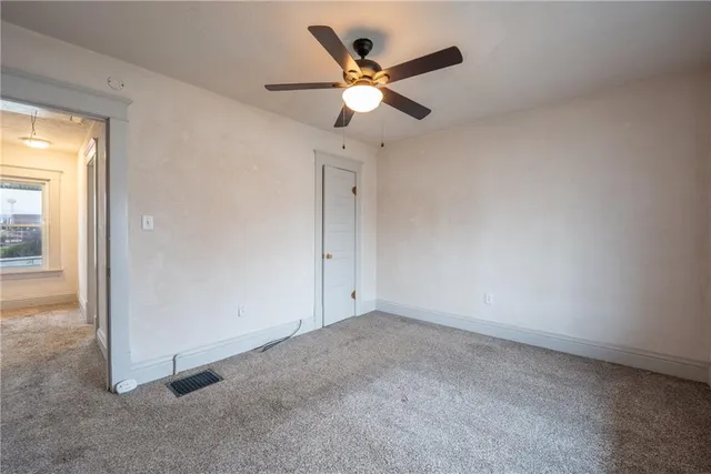an empty room with closet and ceiling fan
