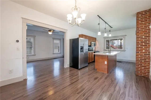 a kitchen with stainless steel appliances granite countertop a refrigerator a stove top oven a sink dishwasher and wooden floor