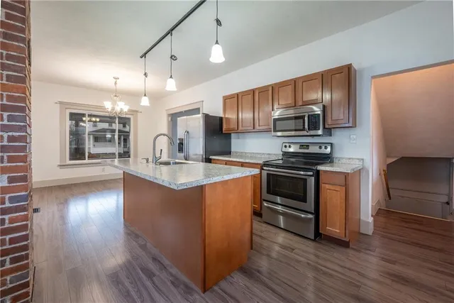 a kitchen with stainless steel appliances kitchen island granite countertop a stove a sink and a refrigerator