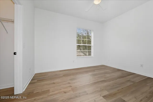 an empty room with wooden floor cabinet and windows
