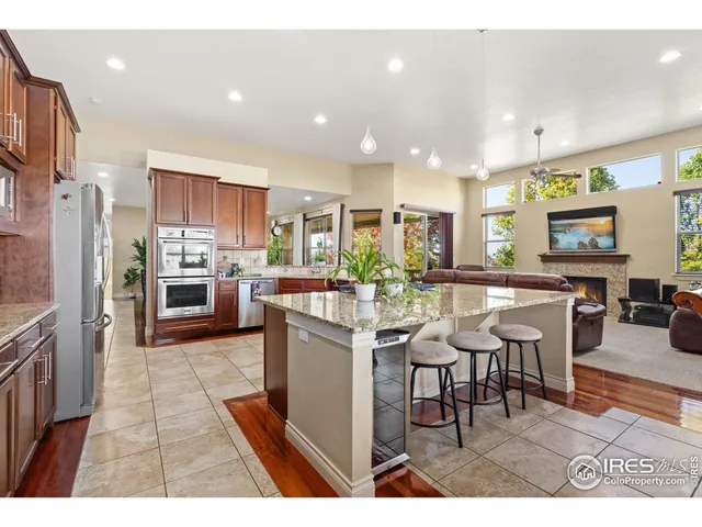 a kitchen with stainless steel appliances kitchen island granite countertop a sink counter space and a view of living room