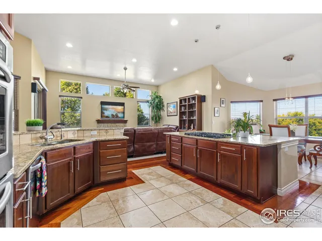 a kitchen with stainless steel appliances kitchen island granite countertop a refrigerator a stove a sink a dining table and chairs