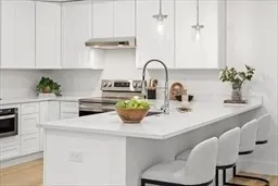 a kitchen with a sink a stove and white cabinets