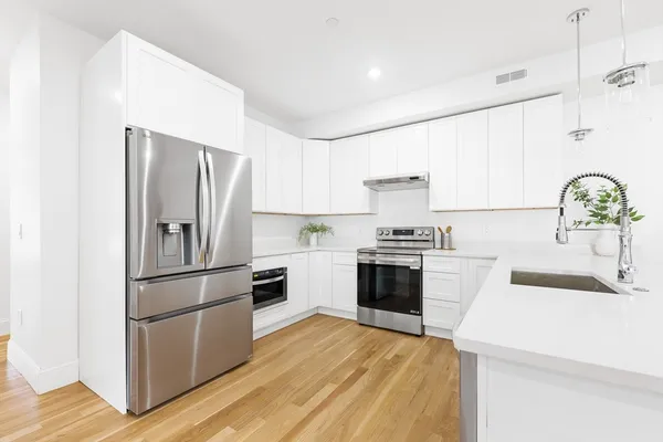 a kitchen with a refrigerator sink and white cabinets
